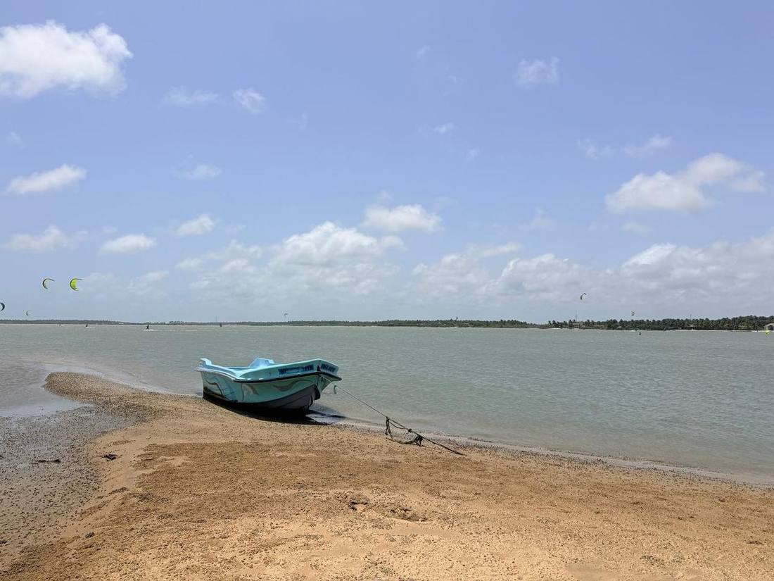Boat on the beach with kitesurfers