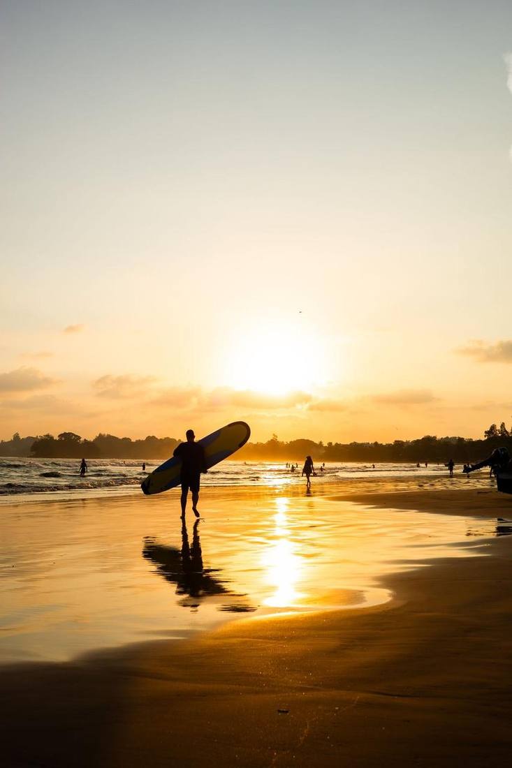 Surfer on Weligama beach at sunset