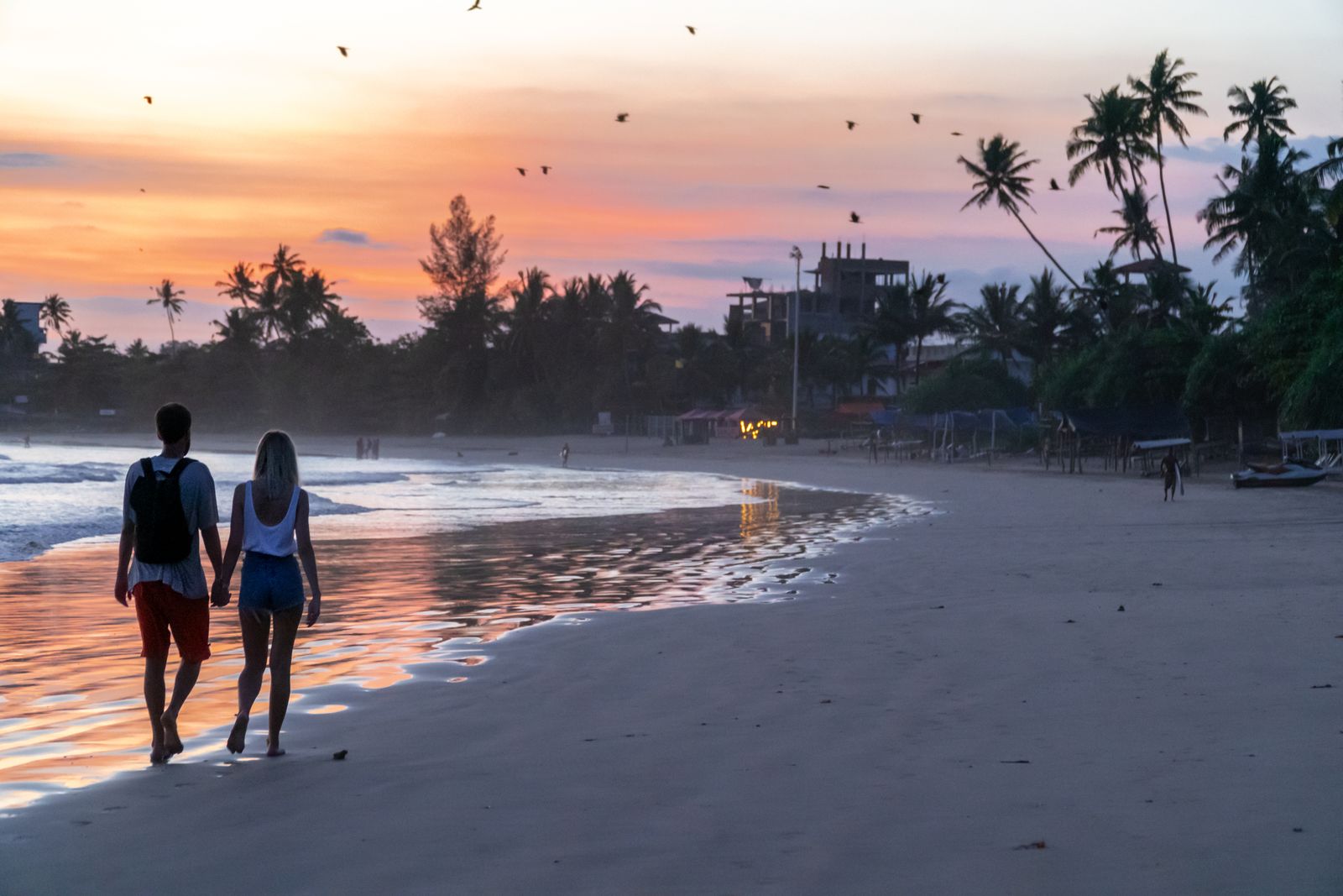 Couple walking along the beach at sunset